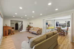 Living area with recessed lighting, crown molding, light wood finished floors, and stairway