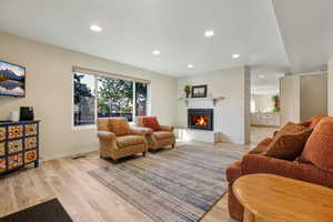 Living room with light wood-style floors, a fireplace, and recessed lighting