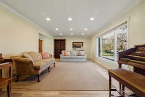 Living room featuring recessed lighting, crown molding, and light wood-style floors