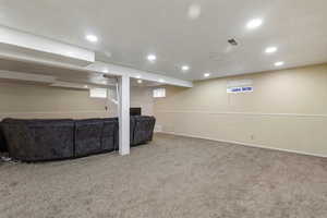 Basement with carpet floors, recessed lighting, and a tiled fireplace