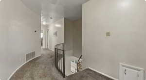 Hall featuring an upstairs landing and carpet flooring