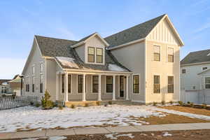 View of front facade featuring board and batten siding, a shingled roof, and covered porch