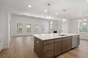 Kitchen with decorative light fixtures, open floor plan, recessed lighting, light wood-style floors, and an island with sink