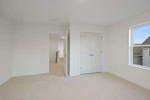 Unfurnished bedroom featuring light colored carpet and a closet