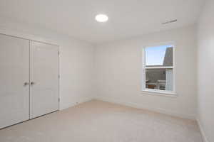 Unfurnished bedroom with light colored carpet and a closet