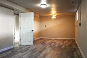 Empty room with dark wood finished floors, a textured ceiling, and ceiling fan