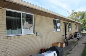 View of property exterior with brick siding and seperate basement entry