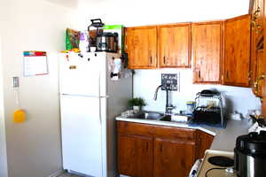 Kitchen with white appliances, brown cabinetry, and light countertops