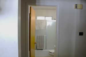 Full bath featuring shower / bath combination with glass door and toilet