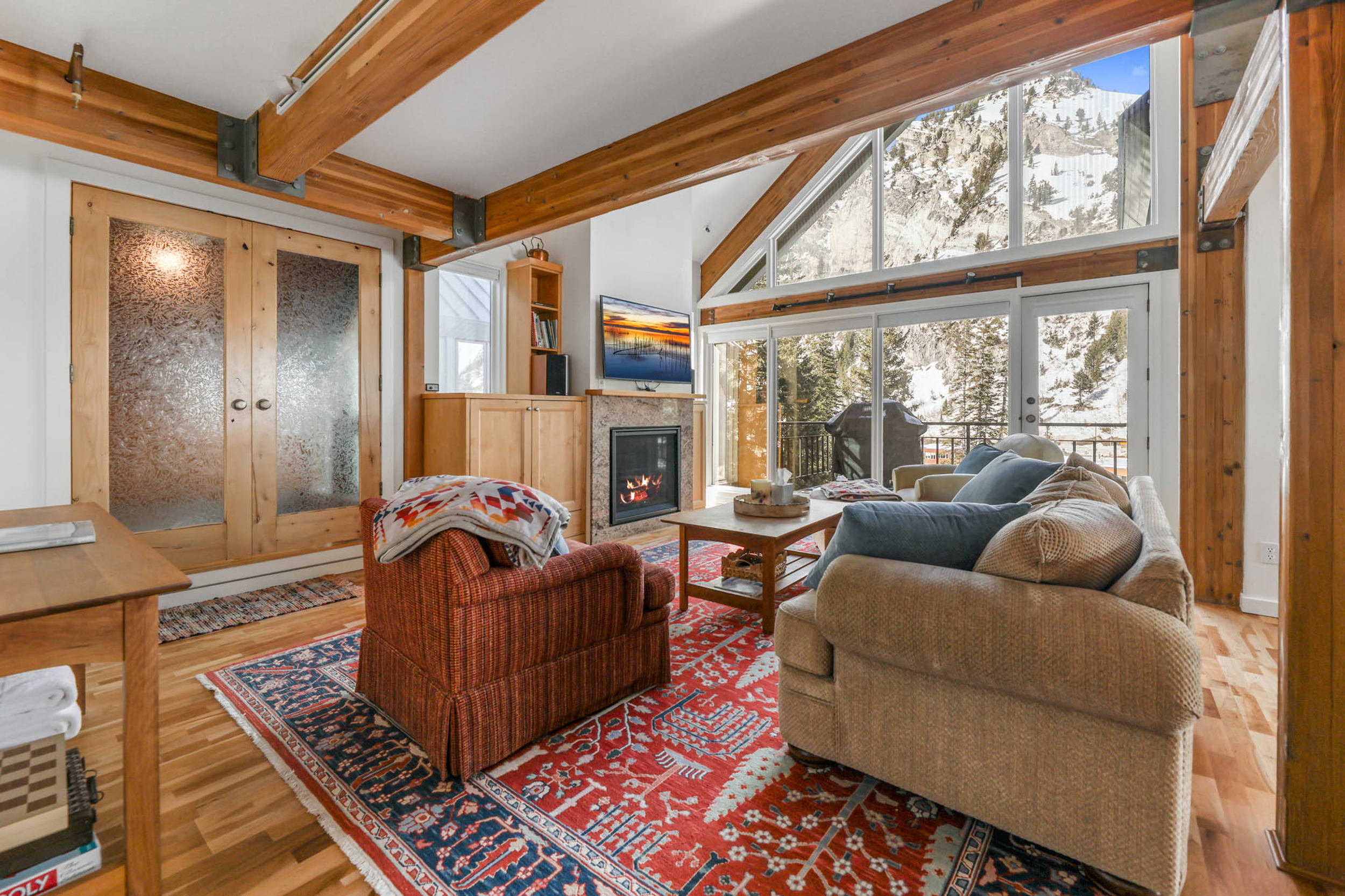 Living room with enclosed hot tub room, a fireplace with flush hearth, gorgeous hardwood floors, and high vaulted beamed ceiling