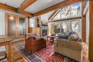 Living room with enclosed hot tub room, a fireplace with flush hearth, gorgeous hardwood floors, and high vaulted beamed ceiling