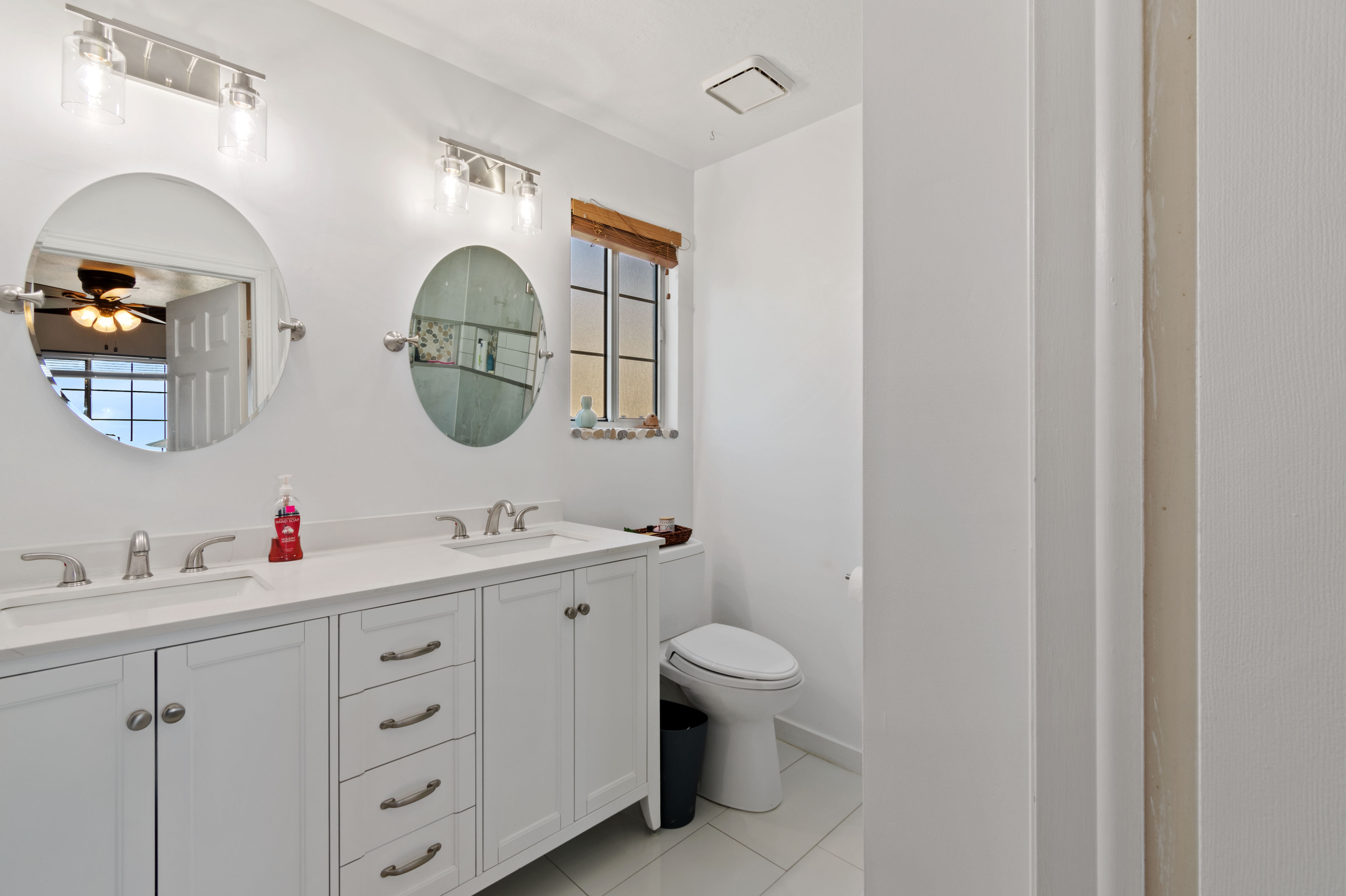 Bathroom featuring double vanity, a ceiling fan, and light tile patterned floors