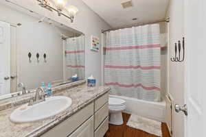Bathroom featuring vanity, shower / tub combo, and dark wood finished floors