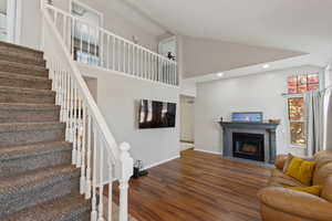 Living room with wood finished floors, a tile fireplace, recessed lighting, and high vaulted ceiling