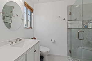 Full bath with a marble finish shower, vanity, and light tile patterned floors