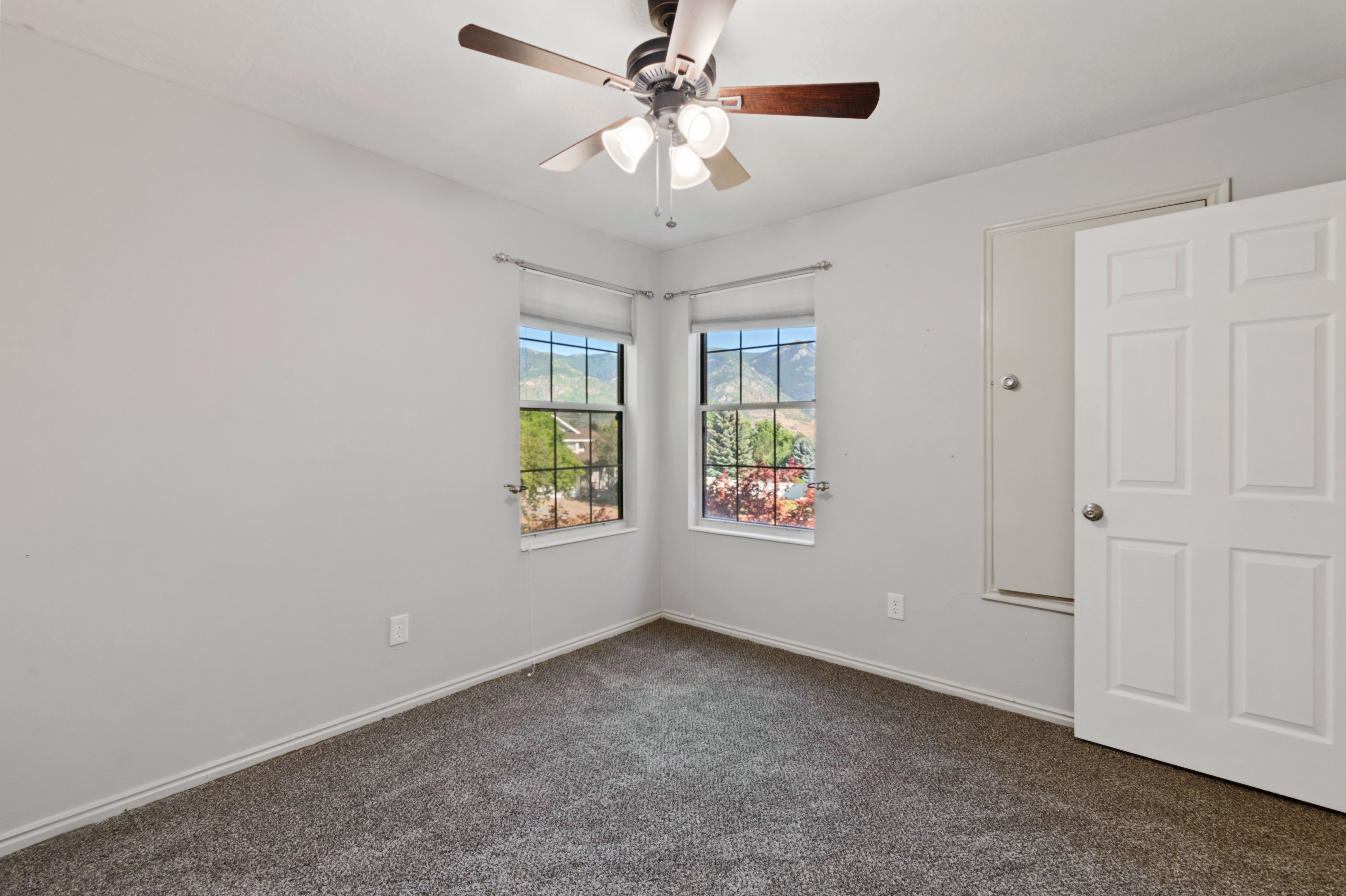Empty room with dark carpet and ceiling fan
