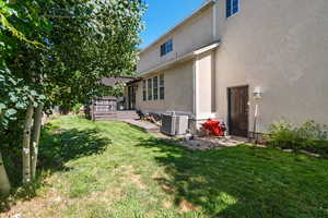Rear view of house featuring a yard, stucco siding, and a deck