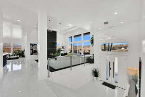 Entryway featuring a fireplace, a towering ceiling, light tile patterned floors, recessed lighting, and a chandelier