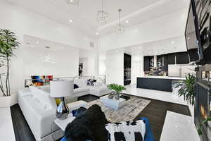 Living area featuring recessed lighting, a towering ceiling, a warm lit fireplace, and dark wood-type flooring