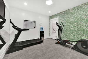 Workout area featuring wallpapered walls, an accent wall, and recessed lighting