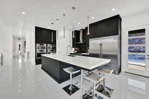 Kitchen featuring dark cabinetry, modern cabinets, appliances with stainless steel finishes, a large island with sink, and recessed lighting