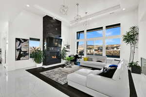 Living room featuring a towering ceiling, a fireplace, a raised ceiling, and recessed lighting