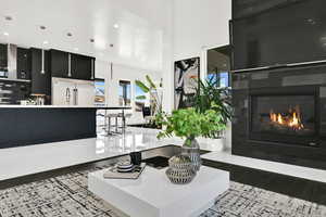 Living room featuring light wood finished floors, a glass covered fireplace, and recessed lighting