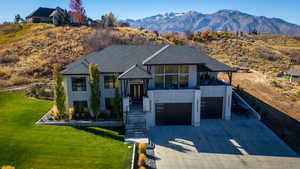 View of front of home featuring a patio area, stucco siding, a mountain view, a front yard, and driveway