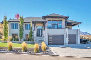 View of front of home with stucco siding, concrete driveway, an attached garage, and a mountain view