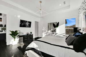 Bedroom with a raised ceiling, dark wood-style flooring, and recessed lighting