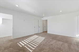 Bedroom featuring light carpet, recessed lighting, and a spacious closet