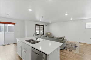 Kitchen featuring white cabinetry, dishwasher, light wood finished floors, a kitchen island with sink, and open floor plan