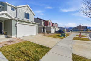 View of side of home with a residential view, driveway, a garage, and a lawn