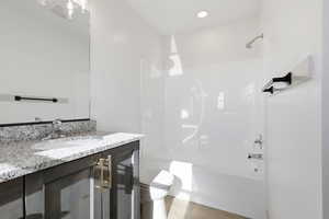 Full bath featuring vanity, washtub / shower combination, and light wood-style floors
