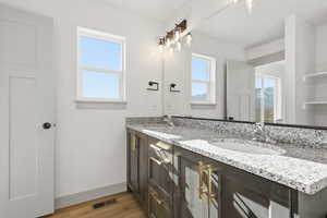 Full bath featuring double vanity and light wood-style flooring