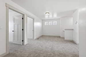 Basement with light colored carpet and baseboards