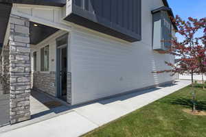 View of side of property with stone siding, a yard, and covered porch