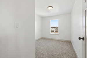 Spare room featuring light carpet and baseboards