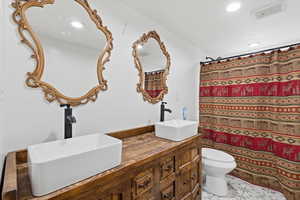Bathroom featuring curtained shower, double vanity, and recessed lighting