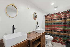 Full bath with double vanity, curtained shower, and recessed lighting