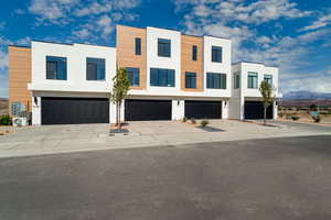 Contemporary home featuring stucco siding, driveway, a mountain view, and a garage