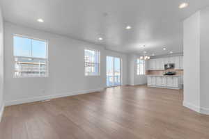 Unfurnished living room with a chandelier and light wood finished floors