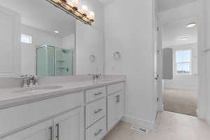 Full bath with a stall shower, double vanity, and light marble finish floors