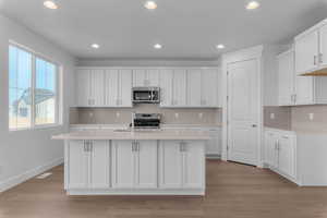 Kitchen with white cabinetry, stainless steel appliances, recessed lighting, a center island with sink, and light wood-style flooring