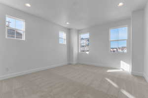 Empty room with light colored carpet and recessed lighting