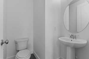 Half bathroom with toilet and baseboards