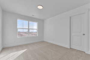 Unfurnished room featuring light carpet and baseboards