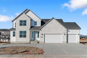 View of front of property with stone siding, concrete driveway, a garage, and roof with shingles