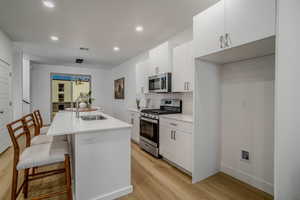 Kitchen with white cabinetry, appliances with stainless steel finishes, a breakfast bar, pendant lighting, and recessed lighting