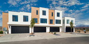 Contemporary home featuring stucco siding, driveway, an attached garage, and a mountain view